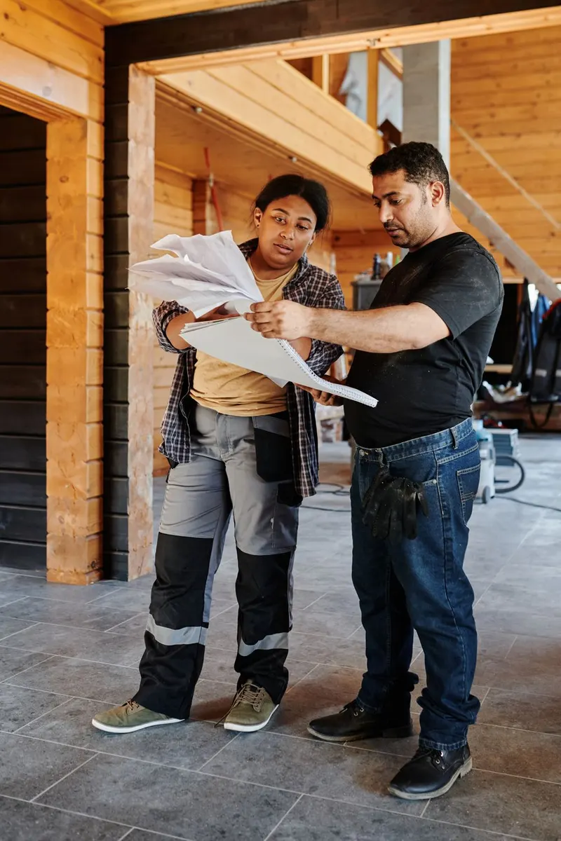 Echipă tehnică analizând planul unei case în construcție